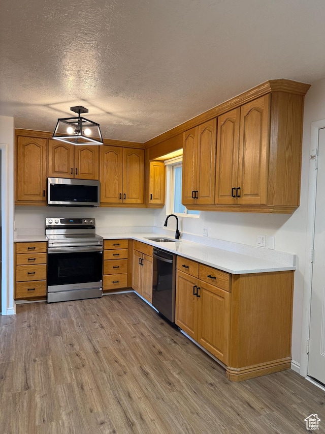 kitchen with light countertops, stainless steel appliances, a sink, and light wood-type flooring