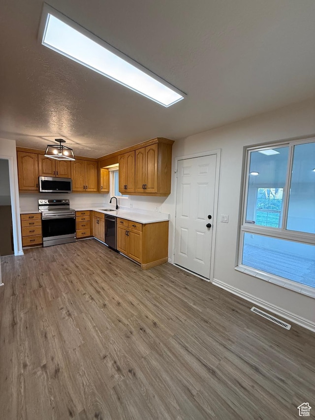 kitchen with a sink, light countertops, stainless steel appliances, wood finished floors, and visible vents
