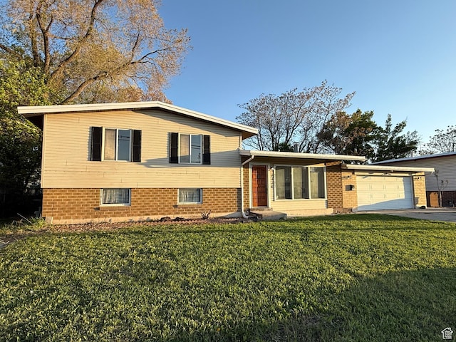 tri-level home featuring a garage, driveway, brick siding, and a front yard