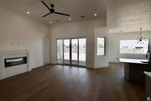 3842 S Kennedy Ln Unit 124, Washington, UT 84780 - unfurnished living room with visible vents, a sink, baseboards, ceiling fan with notable chandelier, and dark wood-style floors
