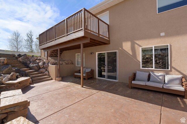 exterior space featuring stairs, an outdoor hangout area, a wooden deck, stucco siding, and a patio