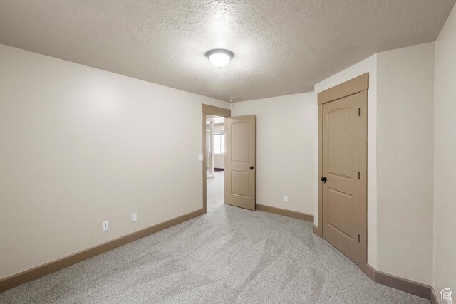 unfurnished room with baseboards, carpet, and a textured ceiling
