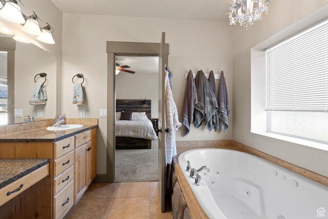 ensuite bathroom with a tub with jets, tile patterned floors, vanity, ceiling fan with notable chandelier, and ensuite bathroom