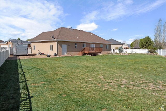 view of yard with a deck, a fenced backyard, a storage unit, a patio area, and an outbuilding