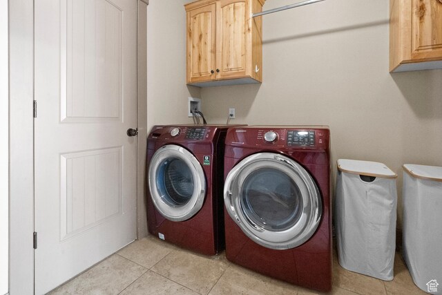 laundry room featuring light tile patterned floors, washing machine and dryer, and cabinet space