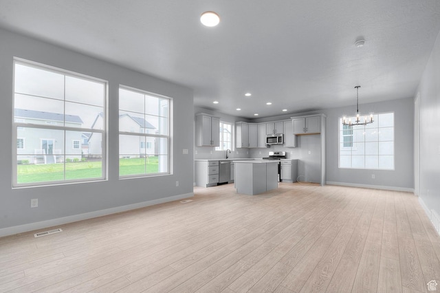 6641 W Spring Snow Ln, Herriman, UT 84096 - kitchen featuring stainless steel appliances, a chandelier, light wood-style flooring, baseboards, and open floor plan