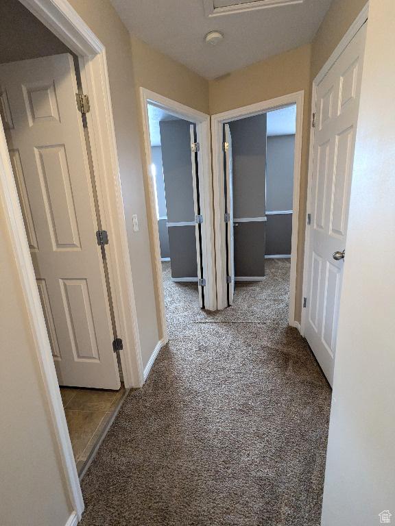corridor featuring baseboards and carpet