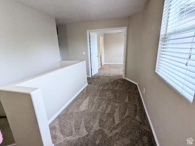 corridor featuring baseboards and carpet flooring