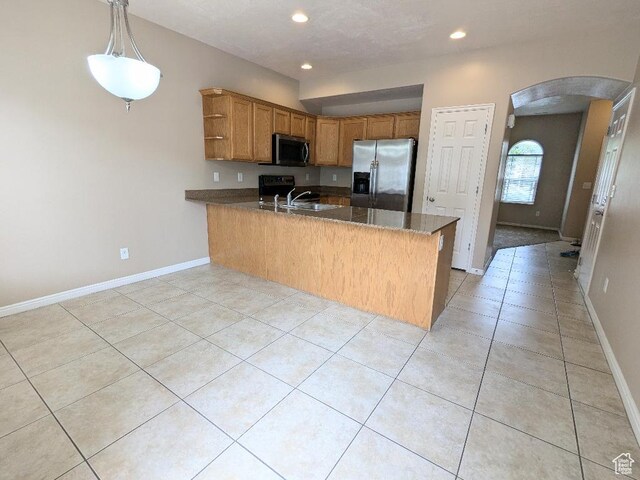 kitchen featuring appliances with stainless steel finishes, arched walkways, a sink, a peninsula, and recessed lighting