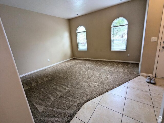 carpeted empty room featuring baseboards, tile patterned floors, and visible vents