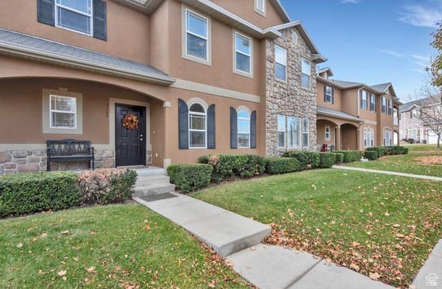 multi unit property with a front yard, a residential view, stone siding, and stucco siding