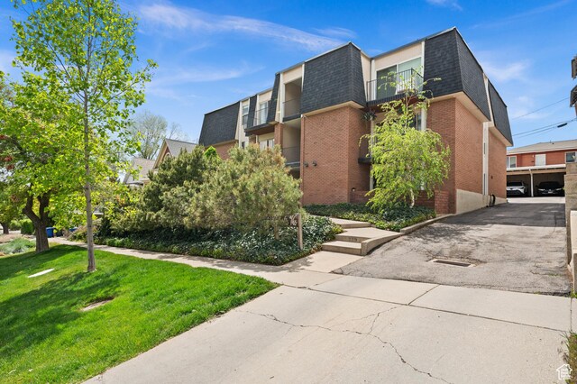 229 N B St Unit 4, Salt Lake City, UT 84103 - view of home's exterior with roof with shingles, brick siding, mansard roof, a balcony, and a yard
