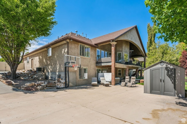 10921 S Renengade View Ln W, South Jordan, UT 84095 - rear view of property featuring a balcony, an outdoor structure, a storage unit, a patio, and stucco siding