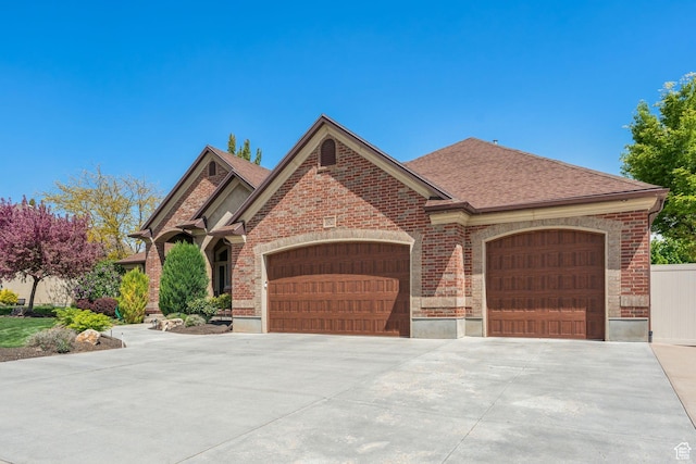 10921 S Renengade View Ln W, South Jordan, UT 84095 - view of front of house featuring a shingled roof, an attached garage, driveway, and brick siding