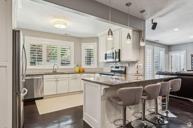 10921 S Renengade View Ln W, South Jordan, UT 84095 - kitchen featuring appliances with stainless steel finishes, tasteful backsplash, a sink, a peninsula, and dark stone counters