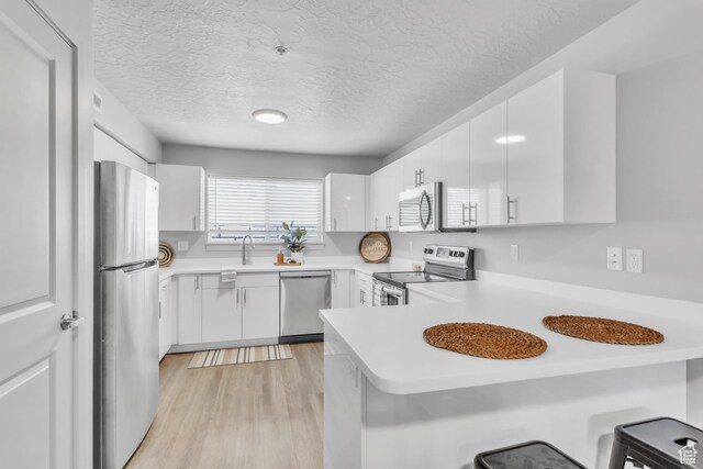 1140 W 950 N Unit E202, Orem, UT 84057 - kitchen featuring a peninsula, appliances with stainless steel finishes, white cabinetry, and a sink