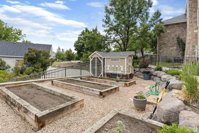 view of yard featuring fence, a garden, and an outdoor structure