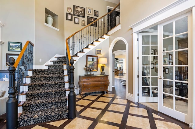 interior space featuring french doors, arched walkways, and a high ceiling