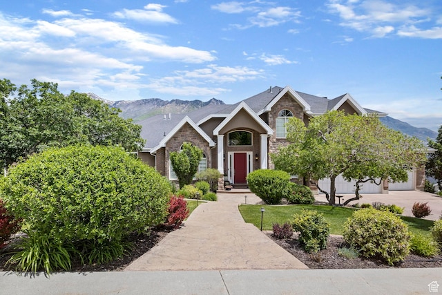 view of front of house with a front lawn, a mountain view, driveway, and stone siding