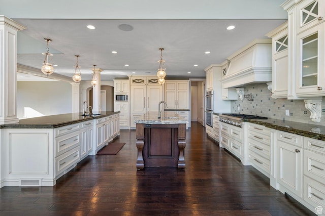 kitchen with a kitchen breakfast bar, a spacious island, custom range hood, a sink, and appliances with stainless steel finishes