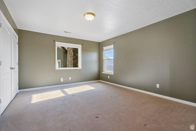 empty room featuring carpet floors, baseboards, and visible vents