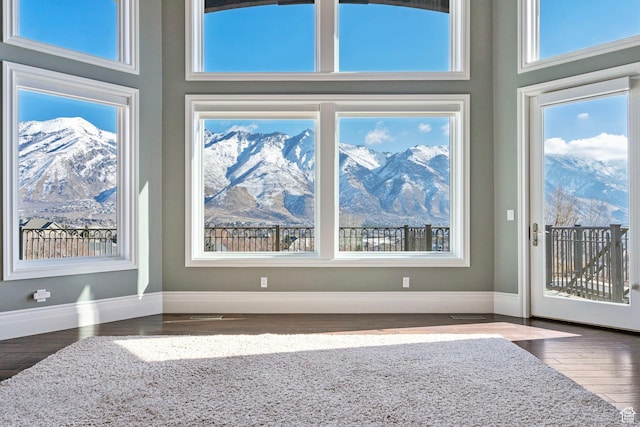 interior space with baseboards, a mountain view, wood finished floors, and a high ceiling