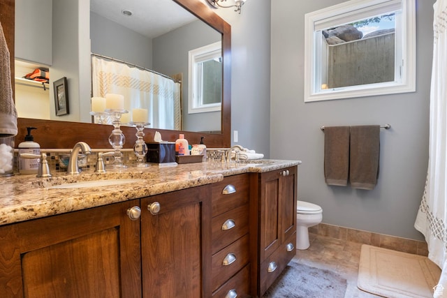 bathroom featuring double vanity, a sink, baseboards, and toilet