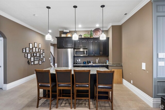 kitchen with arched walkways, stainless steel appliances, baseboards, a kitchen bar, and a kitchen island