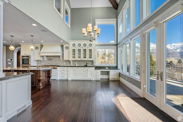interior space featuring custom range hood, a notable chandelier, dark wood-style floors, and oven