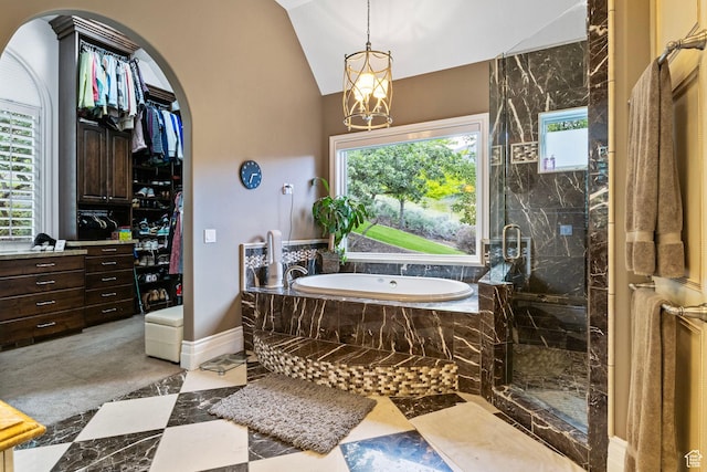 full bath featuring a chandelier, vaulted ceiling, a marble finish shower, and a garden tub
