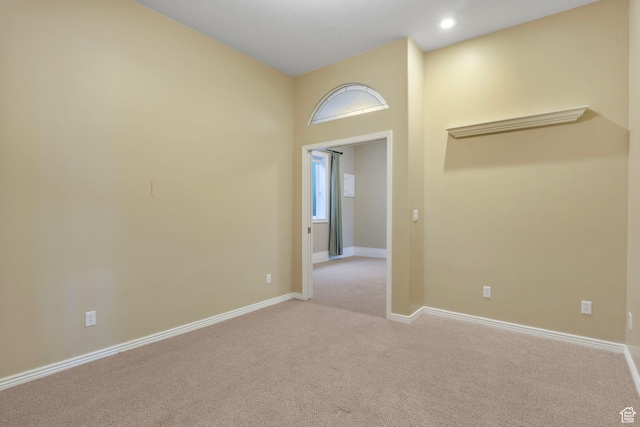 empty room featuring light colored carpet, recessed lighting, and baseboards