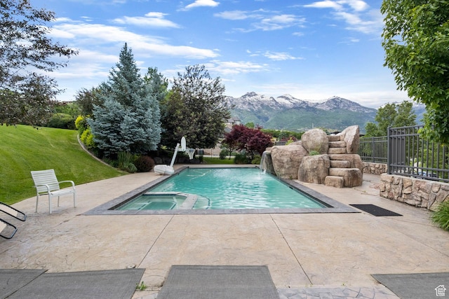 view of swimming pool featuring a patio, a mountain view, a pool with connected hot tub, and fence