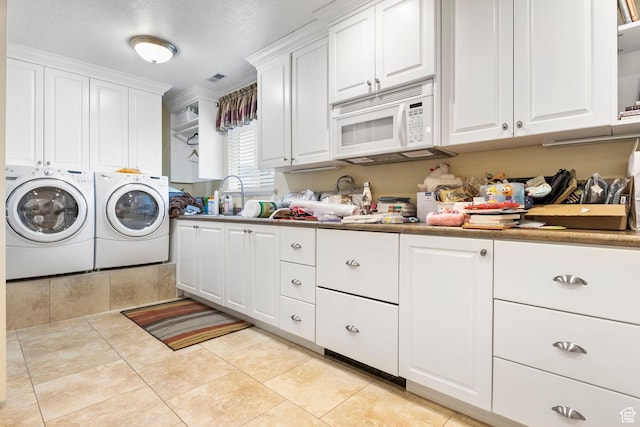 clothes washing area featuring visible vents, cabinet space, a sink, light tile patterned floors, and separate washer and dryer