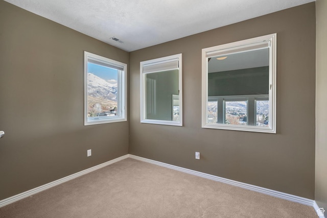 empty room featuring carpet flooring, baseboards, and visible vents