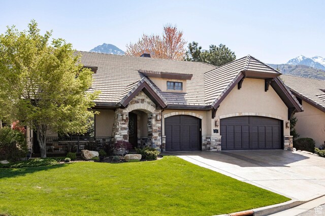 8777 S Falcon Heights Ln E, Cottonwood Heights, UT 84093 - tudor house featuring a front lawn, stone siding, stucco siding, a mountain view, and driveway