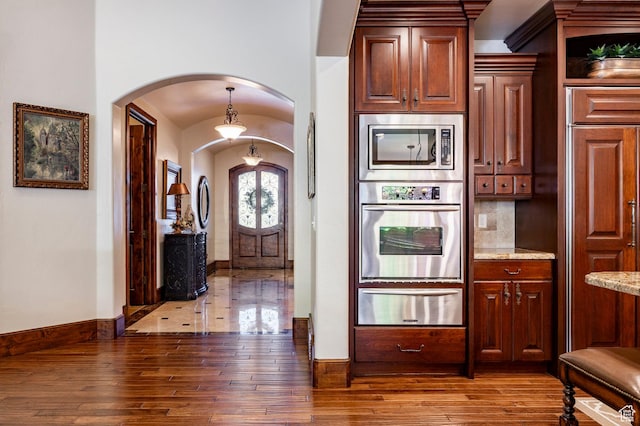 8777 S Falcon Heights Ln E, Cottonwood Heights, UT 84093 - kitchen featuring light stone countertops, appliances with stainless steel finishes, wood-type flooring, arched walkways, and a warming drawer