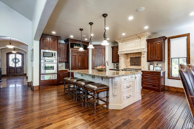 8777 S Falcon Heights Ln E, Cottonwood Heights, UT 84093 - kitchen with a kitchen breakfast bar, a warming drawer, arched walkways, dark wood-style floors, and built in appliances