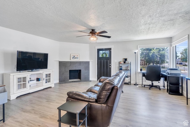 84 W Wasatch St S, Midvale, UT 84047 - living room with wood finished floors, baseboards, a textured ceiling, a tiled fireplace, and a ceiling fan