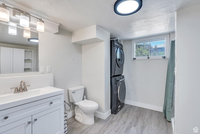 84 W Wasatch St S, Midvale, UT 84047 - bathroom with vanity, stacked washer and dryer, wood finished floors, toilet, and a textured ceiling