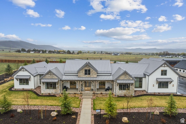 205 W Lazy Acres Ln, Kamas, UT 84036 - view of front facade featuring a standing seam roof, a mountain view, stone siding, and a front lawn