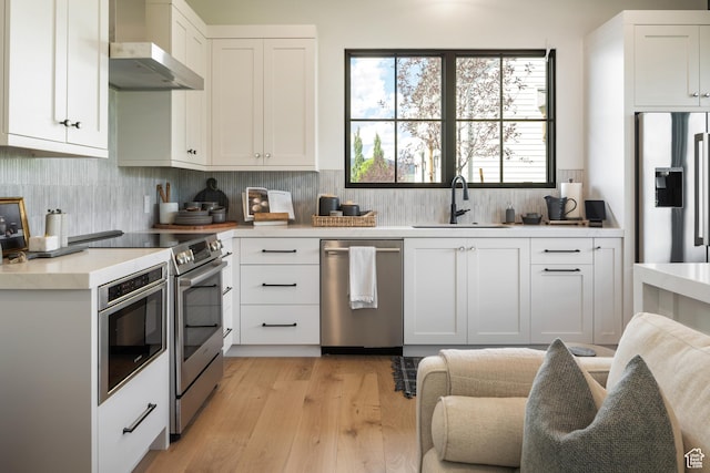 205 W Lazy Acres Ln, Kamas, UT 84036 - kitchen with wall chimney range hood, appliances with stainless steel finishes, a sink, light wood finished floors, and light countertops