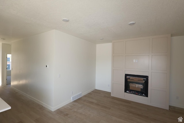 4888 W Coulter Unit 703, Highland, UT 84003 - unfurnished living room with light wood-type flooring, a textured ceiling, and a glass covered fireplace