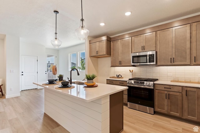 4888 W Coulter Unit 703, Highland, UT 84003 - kitchen featuring stainless steel appliances, light wood-type flooring, decorative backsplash, light countertops, and a center island with sink