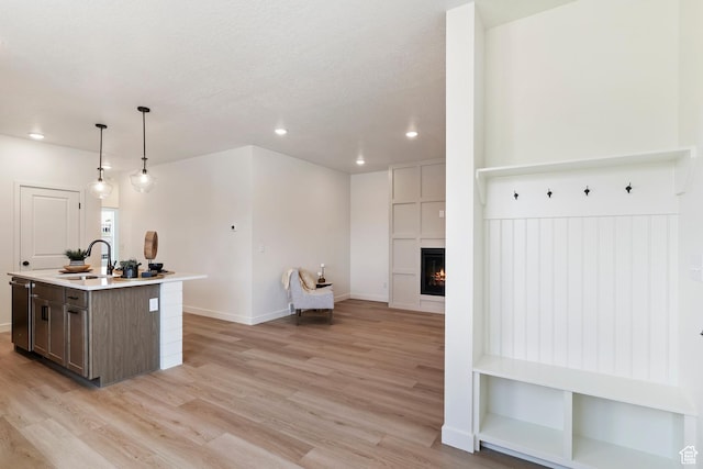 4888 W Coulter Unit 703, Highland, UT 84003 - kitchen featuring light wood-style floors, a kitchen island with sink, recessed lighting, light countertops, and a tile fireplace