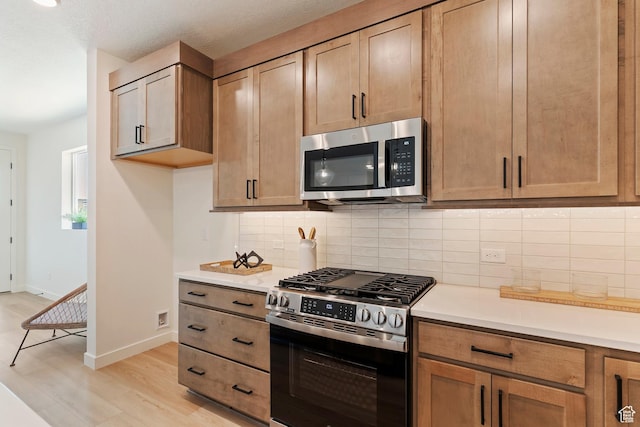 4888 W Coulter Unit 703, Highland, UT 84003 - kitchen featuring appliances with stainless steel finishes, light wood-style flooring, light countertops, and tasteful backsplash