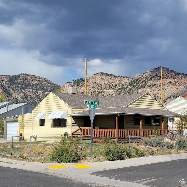207 N Rawlins St, East Carbon, UT 84520 - view of front of property with fence, covered porch, a mountain view, and roof with shingles