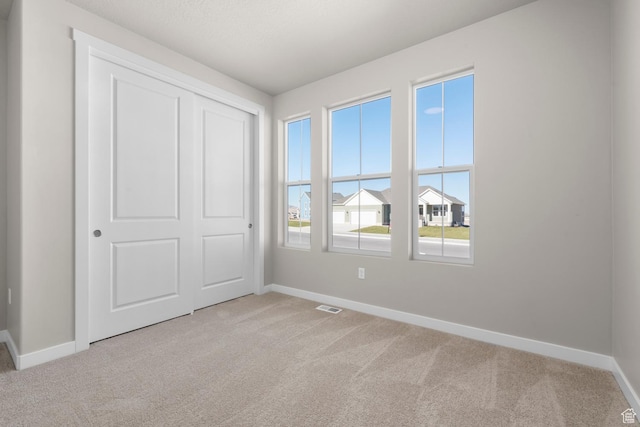 unfurnished bedroom featuring baseboards and light colored carpet