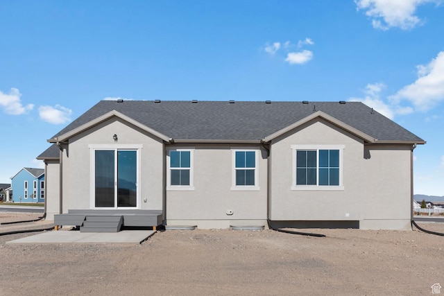 rear view of property featuring roof with shingles and stucco siding