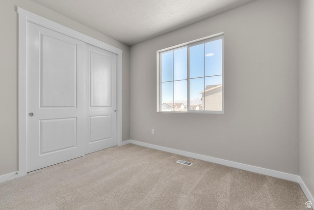 unfurnished bedroom with visible vents, baseboards, and light colored carpet