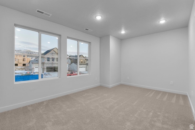 spare room featuring baseboards, visible vents, and light carpet